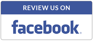 A rectangular sign that reads "Review us on" in white lettering on a blue background, followed by the Facebook logo in blue and white for Emergency Restoration.